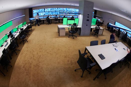 Group of Security data center operators working in a CCTV monitoring room looking on multiple monitors  Officers Monitoring Multiple Screens for Suspicious Activities  Team working on the System Control Room