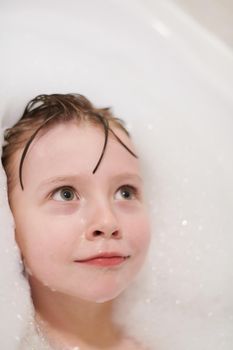 little girl playing with soap foam in bath during coronavirus stay at home pandemic quarantine