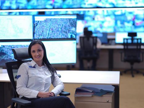 portrait of female security operator while working in a data system control room offices Technical Operator Working at  workstation with multiple displays, security guard working on multiple monitors