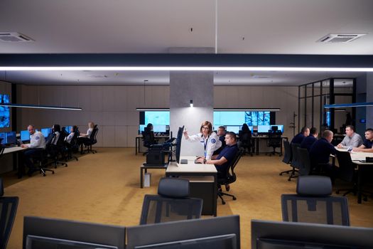 Group of Security data center operators working in a CCTV monitoring room looking on multiple monitors  Officers Monitoring Multiple Screens for Suspicious Activities  Team working on the System Control Room