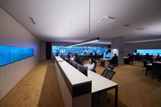 Group of Security data center operators working in a CCTV monitoring room looking on multiple monitors  Officers Monitoring Multiple Screens for Suspicious Activities  Team working on the System Control Room