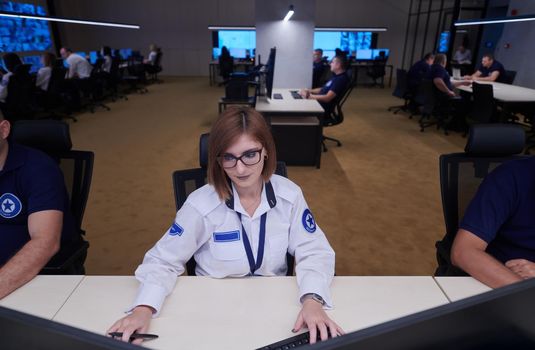 Female security operator working in a data system control room offices Technical Operator Working at  workstation with multiple displays, security guard working on multiple monitors