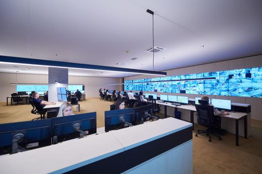 Group of Security data center operators working in a CCTV monitoring room looking on multiple monitors  Officers Monitoring Multiple Screens for Suspicious Activities  Team working on the System Control Room