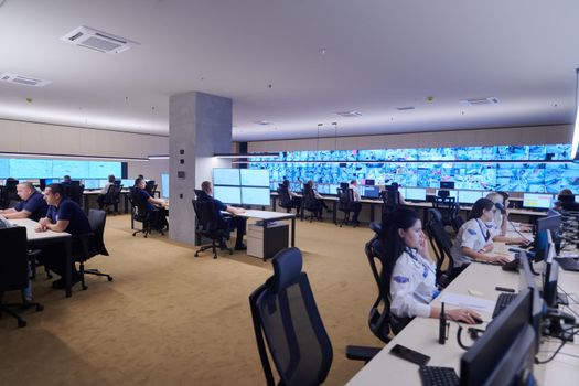 Group of Security data center operators working in a CCTV monitoring room looking on multiple monitors  Officers Monitoring Multiple Screens for Suspicious Activities  Team working on the System Control Room