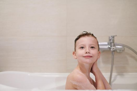 little girl playing with soap foam in bath during coronavirus stay at home pandemic quarantine