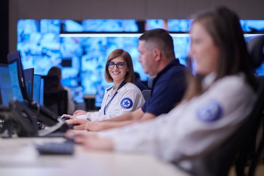 Group of Security data center operators working in a CCTV monitoring room looking on multiple monitors  Officers Monitoring Multiple Screens for Suspicious Activities  Team working on the System Control Room