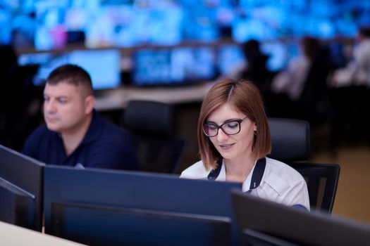 Female security operator working in a data system control room offices Technical Operator Working at  workstation with multiple displays, security guard working on multiple monitors