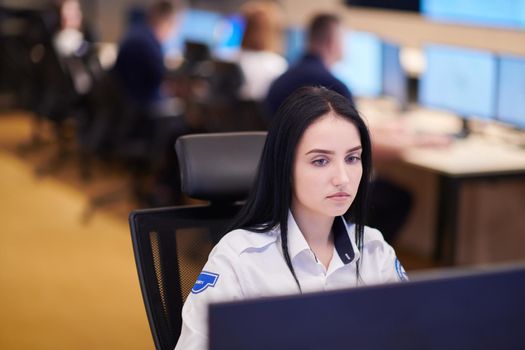 Female security operator working in a data system control room offices Technical Operator Working at  workstation with multiple displays, security guard working on multiple monitors