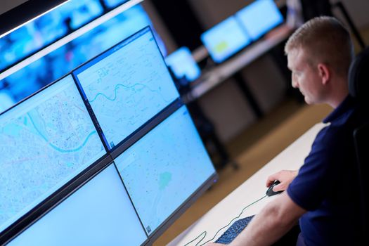 Male security operator working in a data system control room offices Technical Operator Working at  workstation with multiple displays, security guard working on multiple monitors  Male computer operator monitoring from a security center