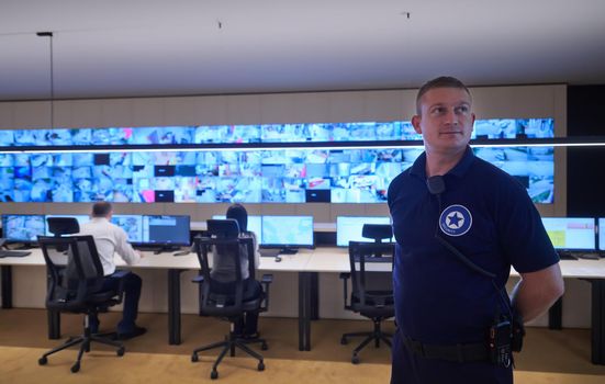 portrait of young male security operator working in a data system control room Working at workstation with multiple displays, security guard working on multiple monitors  Male computer operator monitoring from a security center