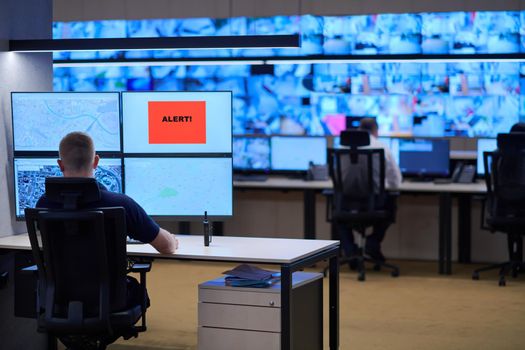 Male security operator working in a data system control room offices Technical Operator Working at  workstation with multiple displays, security guard working on multiple monitors  Male computer operator monitoring from a security center Alarm signal on the screen