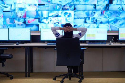 Female security operator working in a data system control room offices Technical Operator Working at  workstation with multiple displays, security guard working on multiple monitors