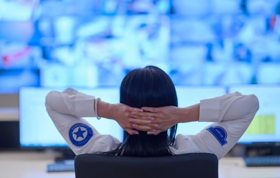 Female security operator working in a data system control room offices Technical Operator Working at  workstation with multiple displays, security guard working on multiple monitors