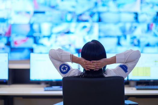 Female security operator working in a data system control room offices Technical Operator Working at  workstation with multiple displays, security guard working on multiple monitors