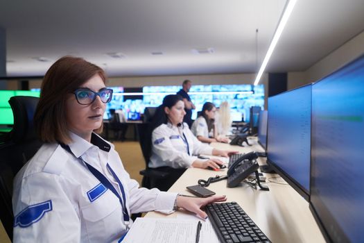 Group of Security data center operators working in a CCTV monitoring room looking on multiple monitors  Officers Monitoring Multiple Screens for Suspicious Activities  Team working on the System Control Room