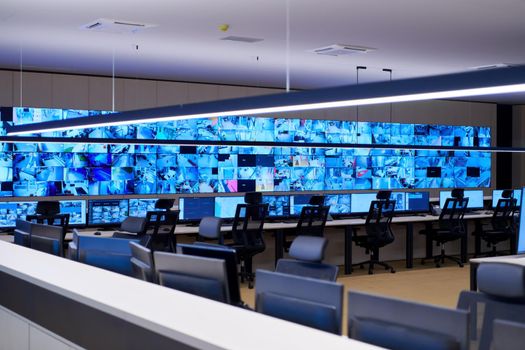 Empty interior of big modern security system control room, workstation with multiple displays, monitoring room with at security data center  Empty office, desk, and chairs at a main CCTV security data center
