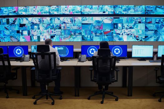 Group of Security data center operators working in a CCTV monitoring room looking on multiple monitors  Officers Monitoring Multiple Screens for Suspicious Activities  Team working on the System Control Room