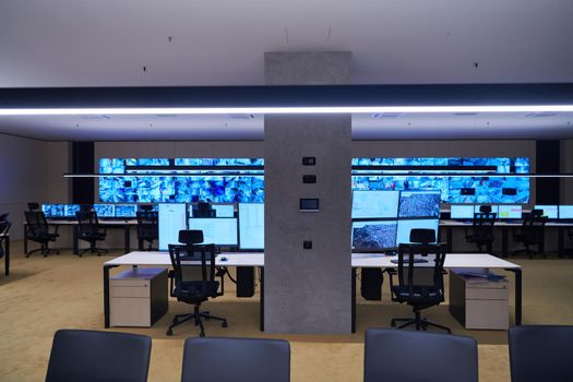 Empty interior of big modern security system control room, workstation with multiple displays, monitoring room with at security data center  Empty office, desk, and chairs at a main CCTV security data center