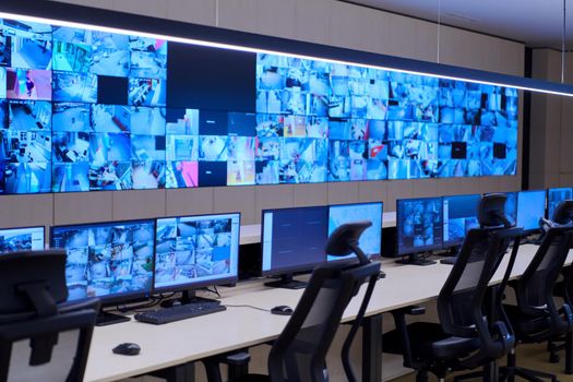 Empty interior of big modern security system control room, workstation with multiple displays, monitoring room with at security data center  Empty office, desk, and chairs at a main CCTV security data center