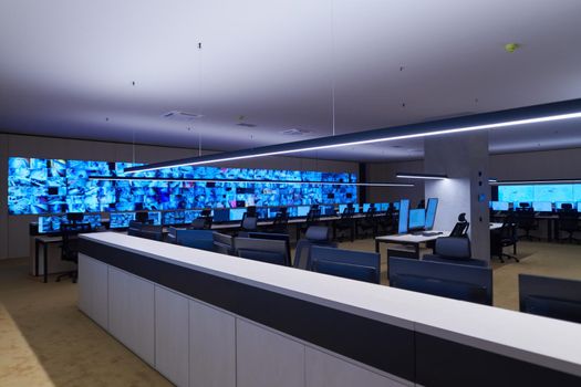 Empty interior of big modern security system control room, workstation with multiple displays, monitoring room with at security data center  Empty office, desk, and chairs at a main CCTV security data center