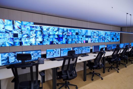 Empty interior of big modern security system control room, workstation with multiple displays, monitoring room with at security data center  Empty office, desk, and chairs at a main CCTV security data center