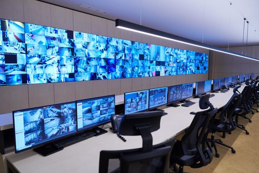 Empty interior of big modern security system control room, workstation with multiple displays, monitoring room with at security data center  Empty office, desk, and chairs at a main CCTV security data center