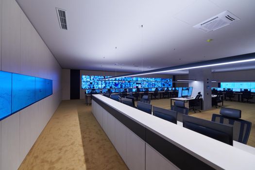 Empty interior of big modern security system control room, workstation with multiple displays, monitoring room with at security data center  Empty office, desk, and chairs at a main CCTV security data center