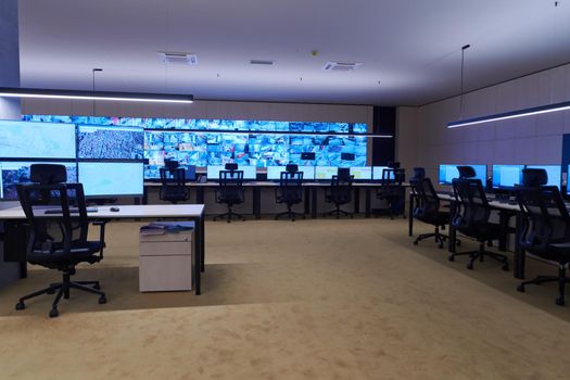 Empty interior of big modern security system control room, workstation with multiple displays, monitoring room with at security data center  Empty office, desk, and chairs at a main CCTV security data center