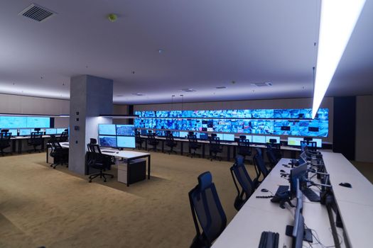 Empty interior of big modern security system control room, workstation with multiple displays, monitoring room with at security data center  Empty office, desk, and chairs at a main CCTV security data center