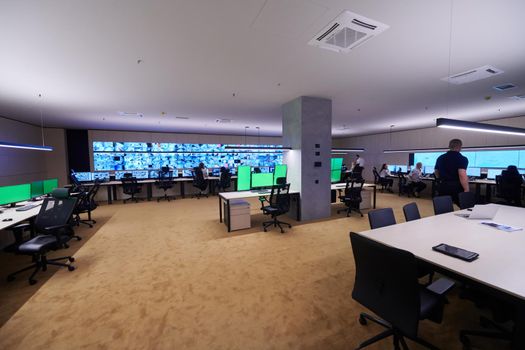 Group of Security data center operators working in a CCTV monitoring room looking on multiple monitors  Officers Monitoring Multiple Screens for Suspicious Activities  Team working on the System Control Room