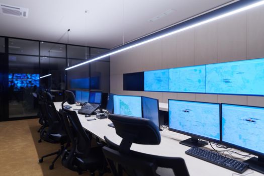 Empty interior of big modern security system control room, workstation with multiple displays, monitoring room with at security data center  Empty office, desk, and chairs at a main CCTV security data center