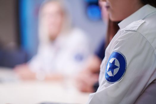 Group of security guards sitting and having briefing In the system control room  They're working in security data center surrounded by multiple Screens