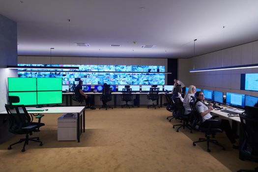 Group of Security data center operators working in a CCTV monitoring room looking on multiple monitors  Officers Monitoring Multiple Screens for Suspicious Activities  Team working on the System Control Room