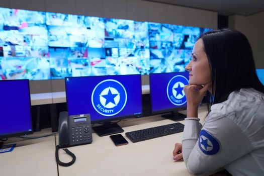 Female security operator working in a data system control room offices Technical Operator Working at  workstation with multiple displays, security guard working on multiple monitors