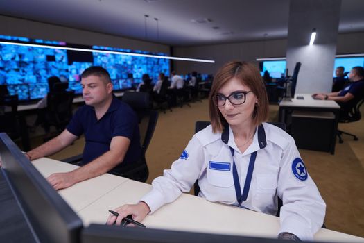 Female security operator working in a data system control room offices Technical Operator Working at  workstation with multiple displays, security guard working on multiple monitors