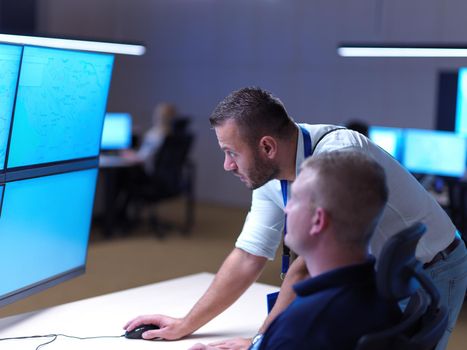 Male security operators working in a data system control room offices Technical Operator Working at  workstation with multiple displays, security guard working on multiple monitors  Male computer operator monitoring from a security center