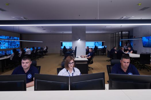 Group of Security data center operators working in a CCTV monitoring room looking on multiple monitors  Officers Monitoring Multiple Screens for Suspicious Activities  Team working on the System Control Room