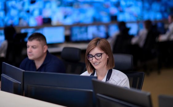 Group of Security data center operators working in a CCTV monitoring room looking on multiple monitors  Officers Monitoring Multiple Screens for Suspicious Activities  Team working on the System Control Room