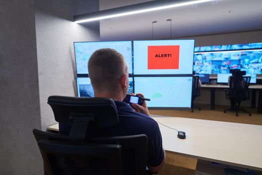 Male security operator working in a data system control room offices Technical Operator Working at  workstation with multiple displays, security guard working on multiple monitors  Male computer operator monitoring from a security center Alarm signal on the screen