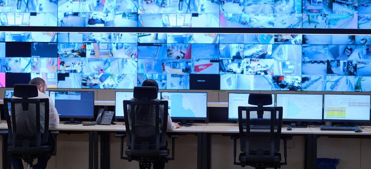 Group of Security data center operators working in a CCTV monitoring room looking on multiple monitors  Officers Monitoring Multiple Screens for Suspicious Activities  Team working on the System Control Room