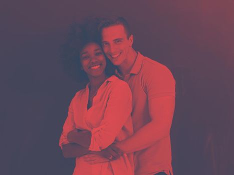 Young happy multiethnic couple laughing and hugging in front of gray chalkboard