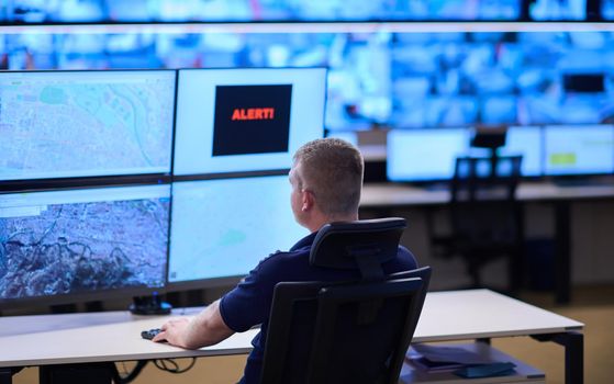 Male security operator working in a data system control room offices Technical Operator Working at  workstation with multiple displays, security guard working on multiple monitors  Male computer operator monitoring from a security center Alarm signal on the screen