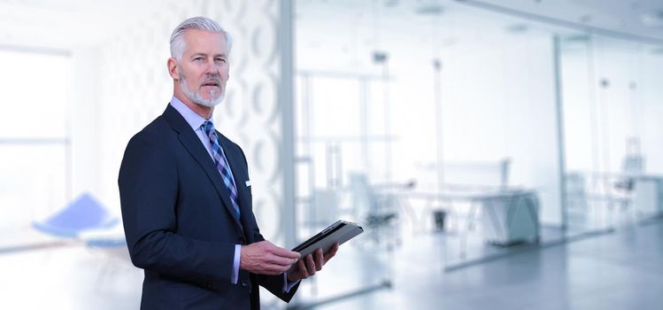 Portrait of senior businessman using tablet in front of his modern office