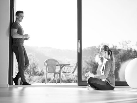 young beautiful handsome couple enjoying morning coffee and Yoga exercises on the door of their luxury home villa