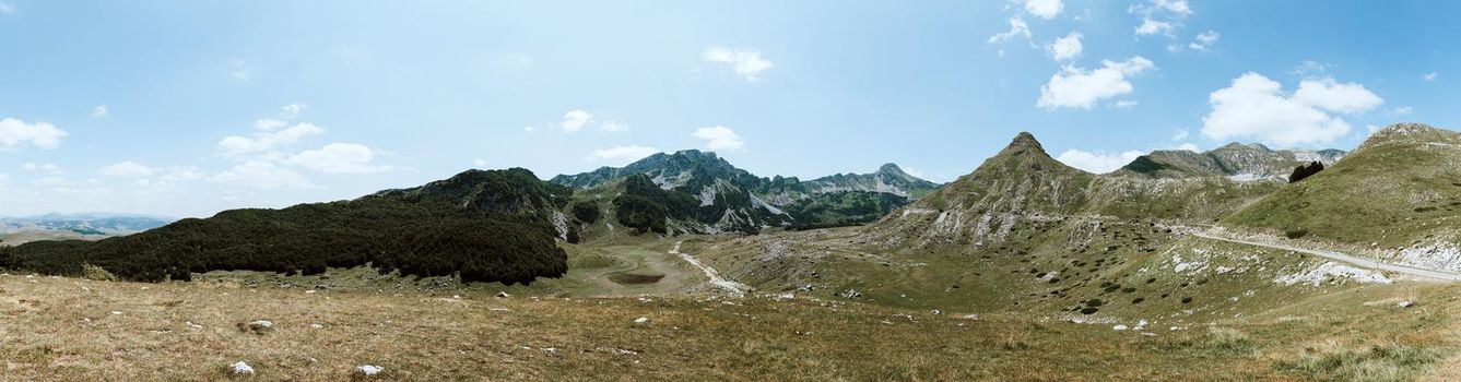 Mountain landscape. Alps with green grass and bright blue sky. Idyllic panorama. Tourism concept. Hiking. Vacation in Europe. Relax in the open air and the spirit of adventure. Ecology of nature.