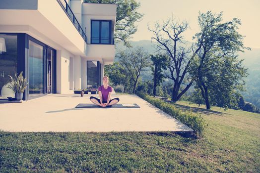 handsome woman doing morning yoga exercises in front of her luxury home villa