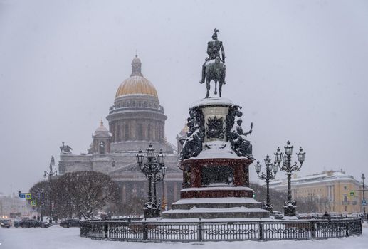 Saint-Petersburg, Russia. - December 04, 2021. View of St. Isaac's Cathedral and equestrian statue of Emperor Nicholas 1. Snowfall, frosty winter weather. Selective focus.