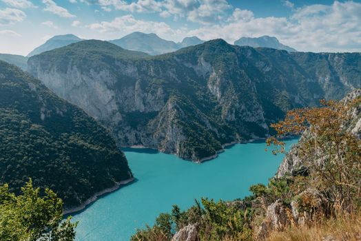 The concept of eco-tourism and active recreation. National Park. Mountain Emerald lake in the wooded mountains. Sunny day in autumn.