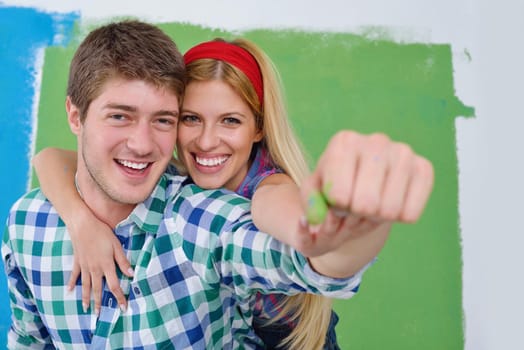 happy young couple paint in green and blue color white wall of their new home