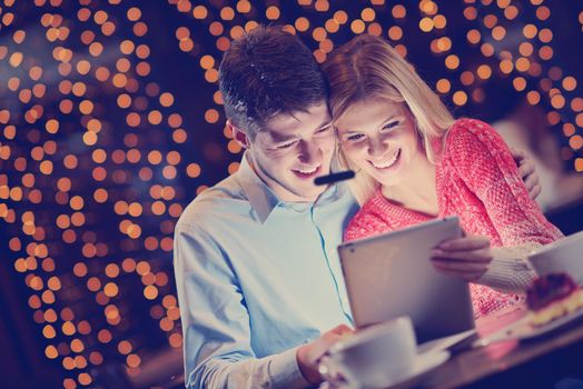 happy young couple with a tablet computer in restaurant